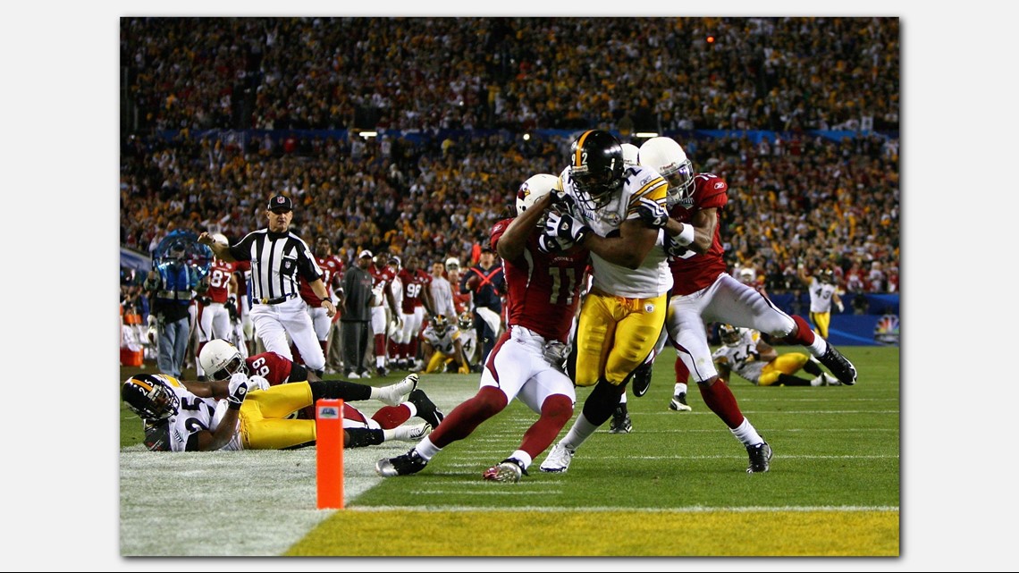 Arizona Cardinals Larry Fitzgerald jumps to catch the football for a  37-yard gain in front of St. Louis Rams Aeneas Williams (35) and Jerametius  Butler (23) for the first play of the