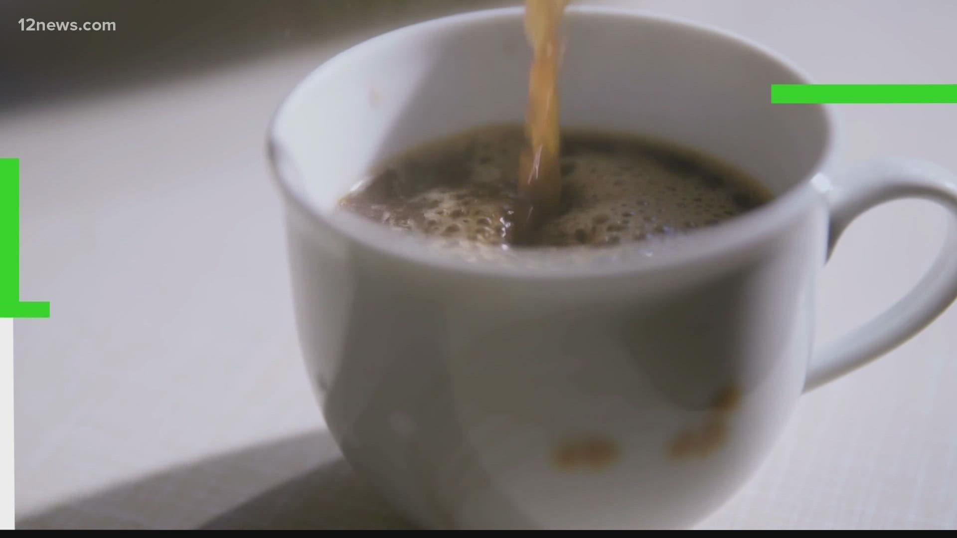 Close-up of hot liquid being poured into a white ceramic mug, creating ripples and foam