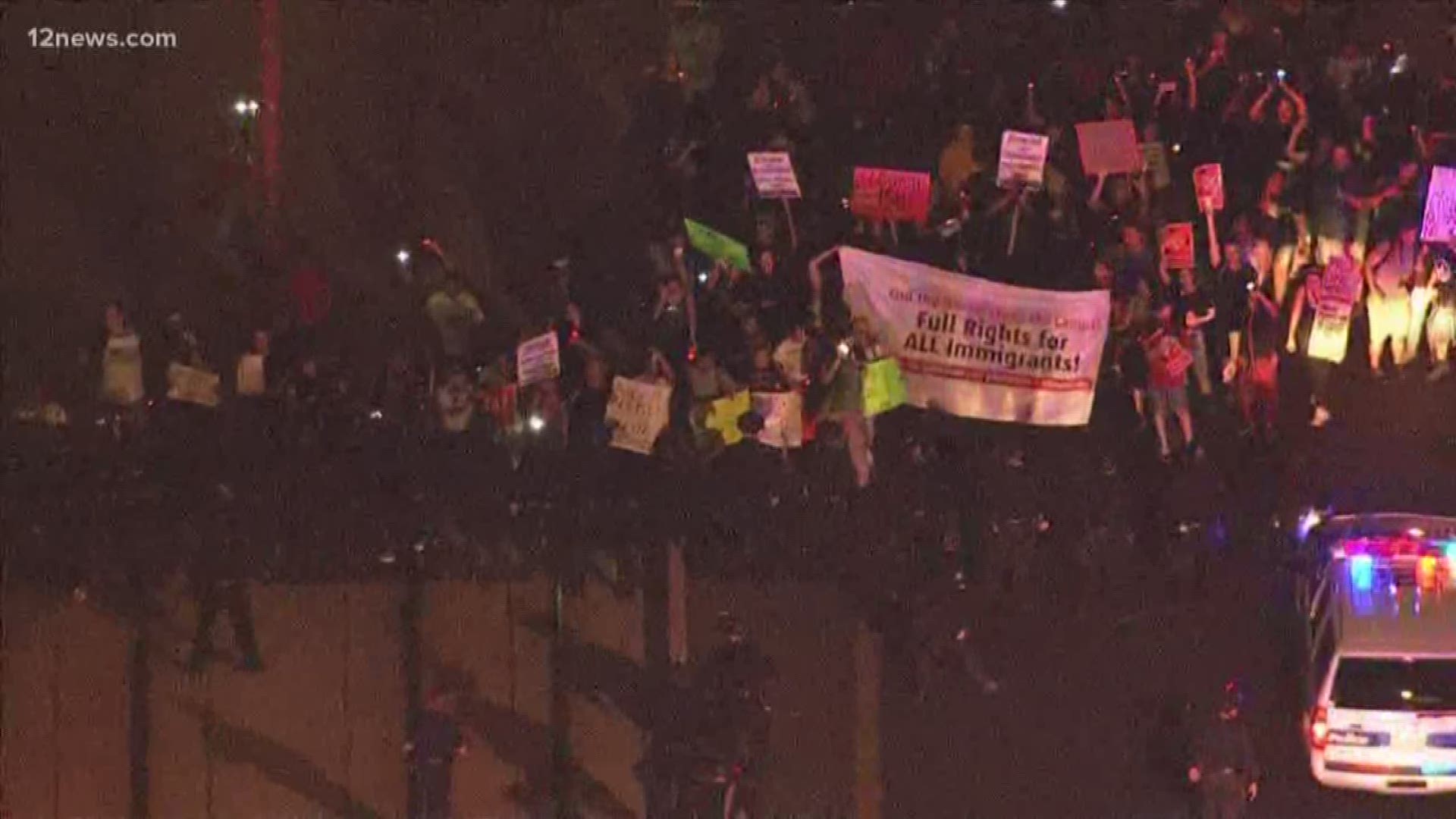 Dozens of protesters were blocking a downtown Phoenix street outside an Immigration and Customs Enforcement office ahead of federal roundups expected Sunday.