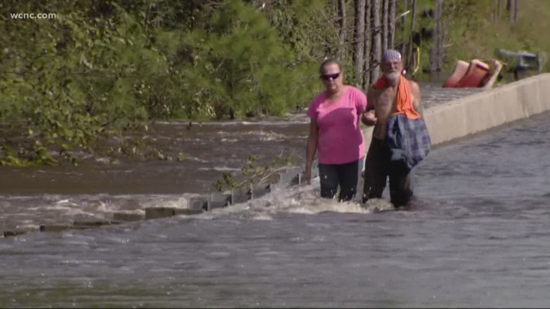A couple was rescued after they fell into floodwaters as they attempted to cross a flooded bridge.